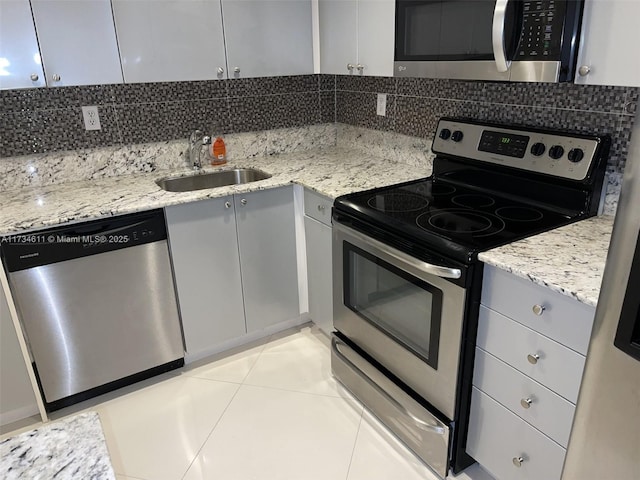 kitchen with gray cabinetry, sink, light stone countertops, and appliances with stainless steel finishes