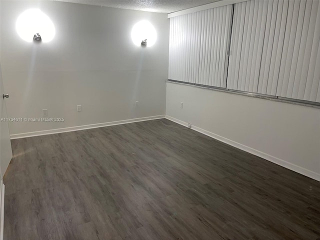 spare room featuring dark wood-type flooring and a textured ceiling