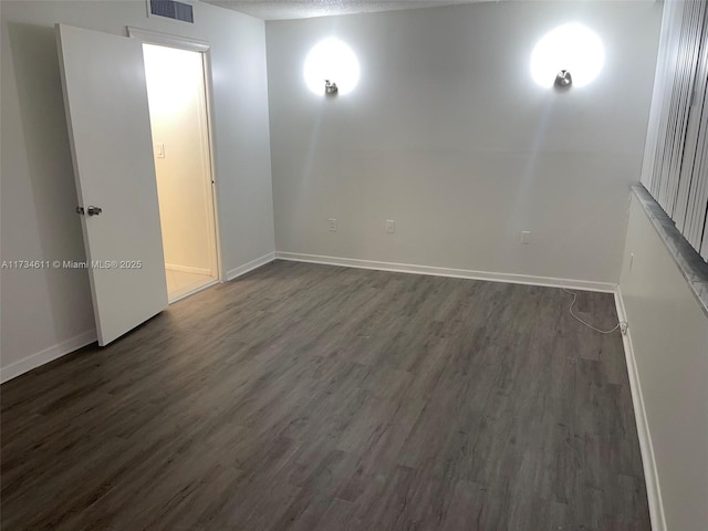 spare room featuring dark hardwood / wood-style floors and a textured ceiling