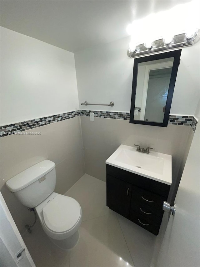 bathroom featuring vanity, toilet, and tile walls