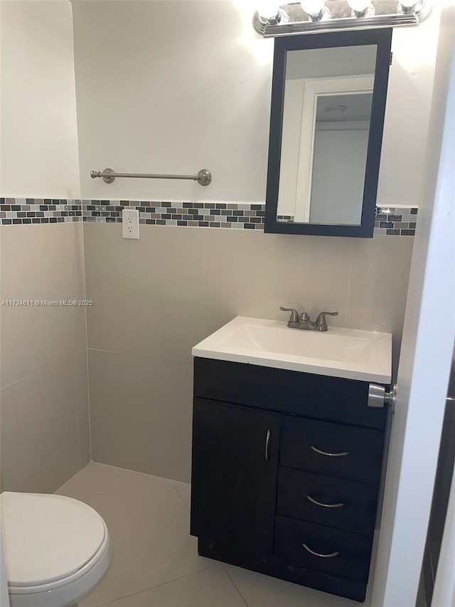 bathroom featuring tile patterned flooring, vanity, tile walls, and toilet