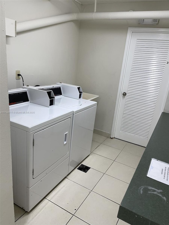 laundry room featuring washing machine and clothes dryer and light tile patterned floors