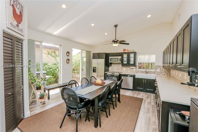 dining room featuring ceiling fan, sink, light hardwood / wood-style floors, and vaulted ceiling