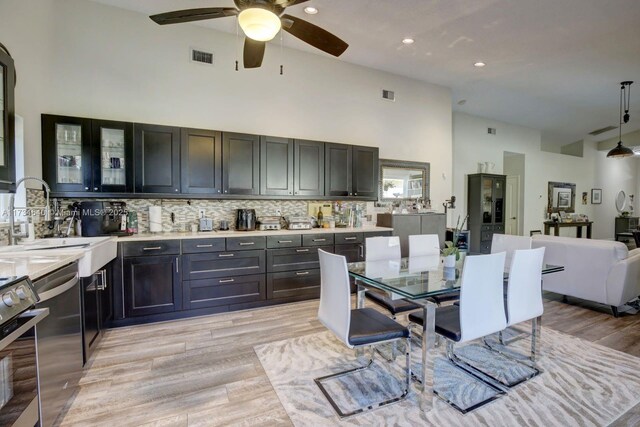 dining space featuring ceiling fan, lofted ceiling, sink, and light hardwood / wood-style floors