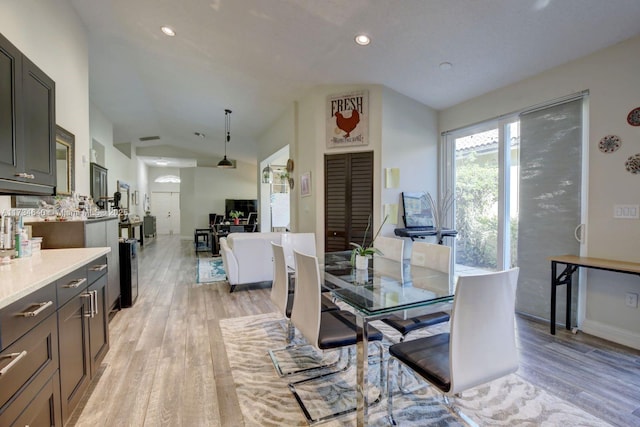 dining space with vaulted ceiling and light wood-type flooring