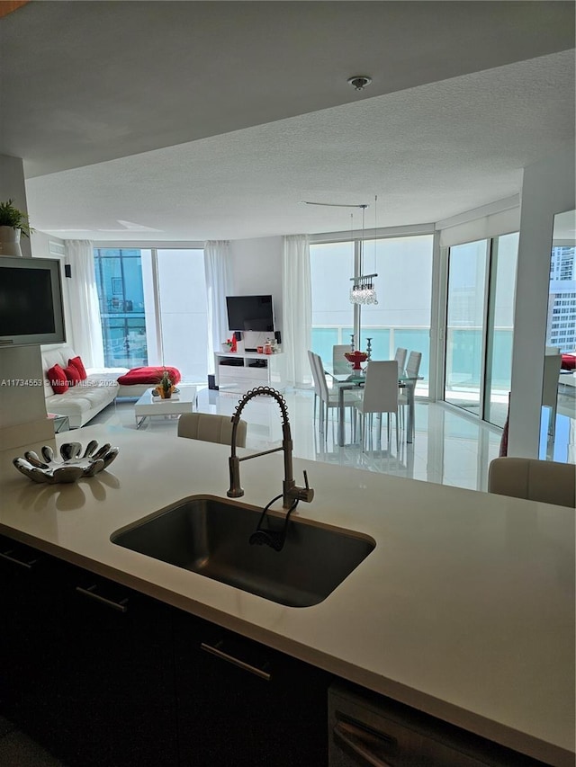 kitchen with sink, decorative light fixtures, a textured ceiling, and black dishwasher