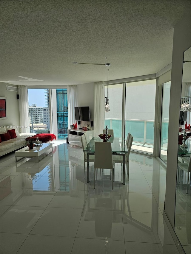 dining space featuring light tile patterned floors, a wall of windows, and a textured ceiling