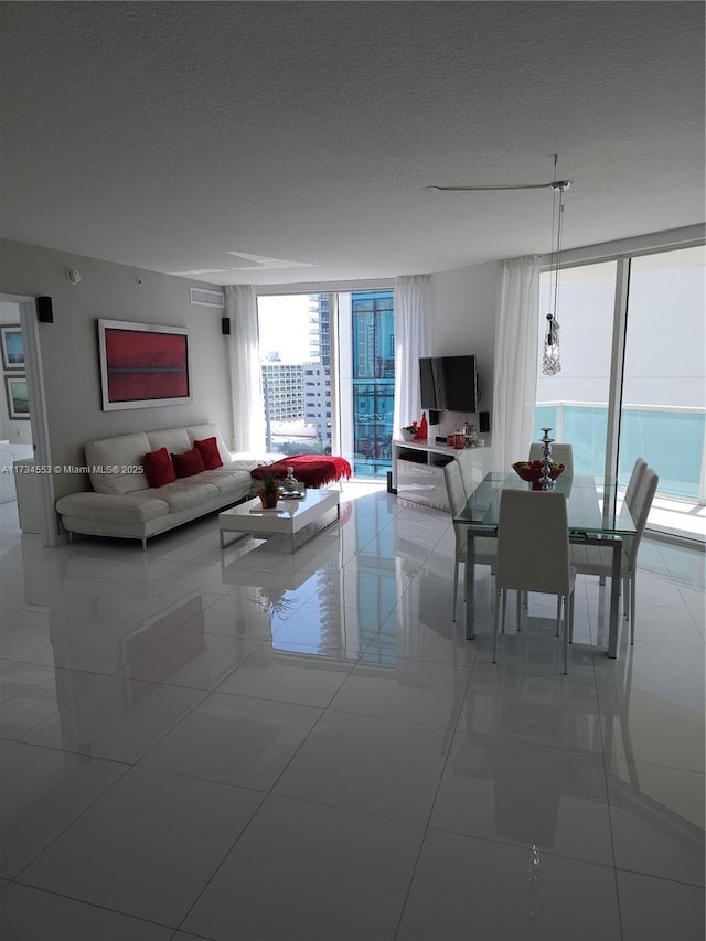 living room featuring light tile patterned floors, a wall of windows, and a textured ceiling