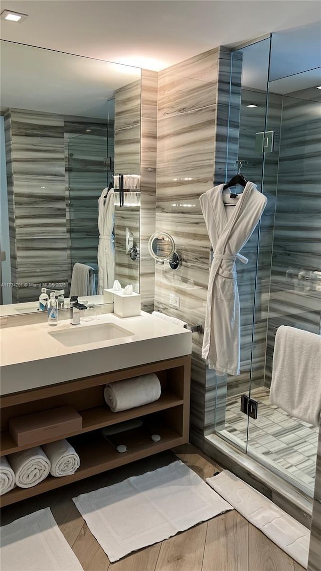 bathroom with hardwood / wood-style flooring, vanity, and an enclosed shower