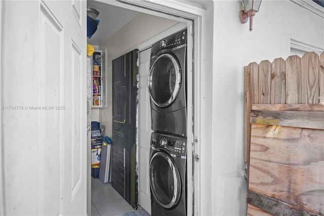 clothes washing area featuring tile patterned flooring and stacked washer and clothes dryer