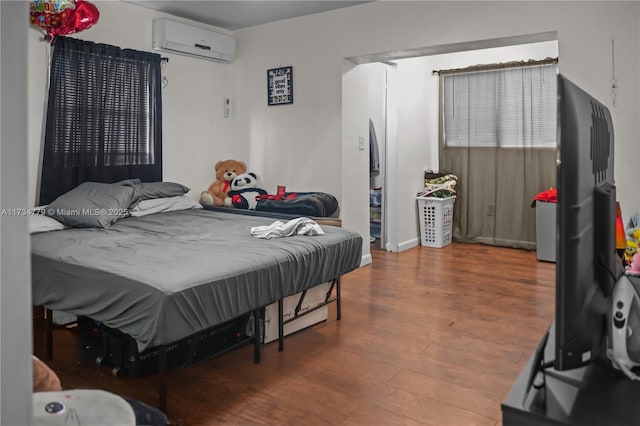 bedroom featuring a wall mounted air conditioner and hardwood / wood-style floors