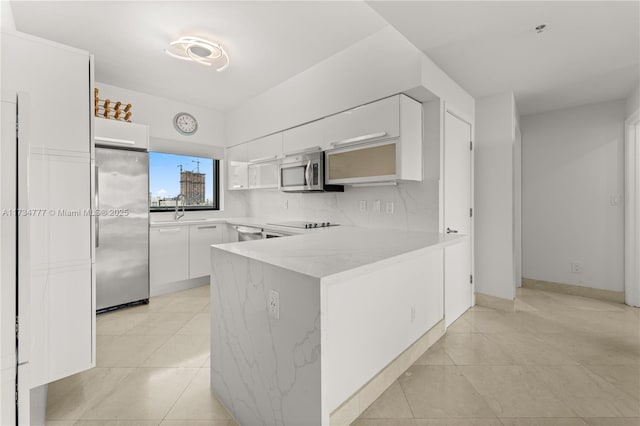 kitchen featuring stainless steel appliances, white cabinetry, sink, and kitchen peninsula