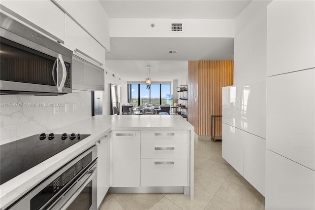 kitchen with pendant lighting, white cabinetry, backsplash, stainless steel appliances, and kitchen peninsula