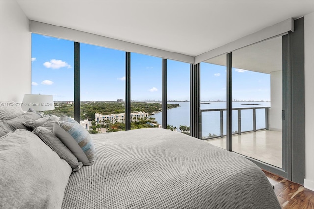 bedroom featuring a water view, floor to ceiling windows, hardwood / wood-style floors, and multiple windows