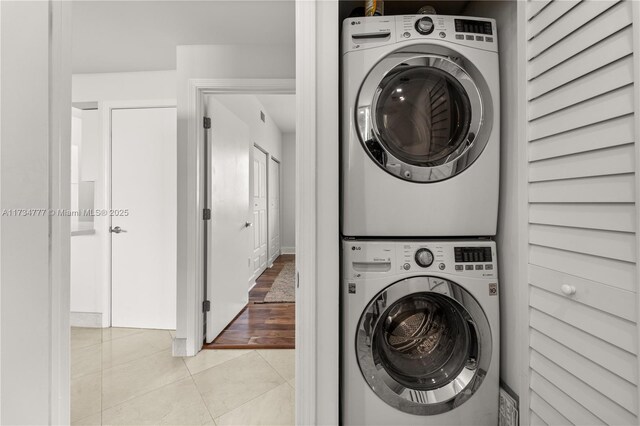 clothes washing area with stacked washing maching and dryer and light tile patterned floors