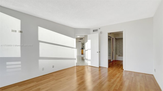 unfurnished room featuring a textured ceiling and light wood-type flooring