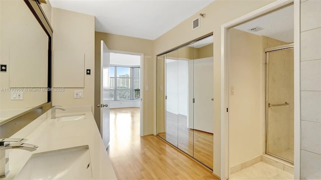 bathroom featuring vanity, a shower with shower door, and wood-type flooring