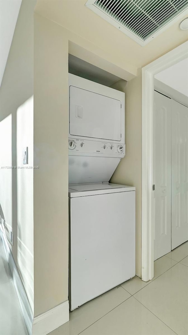 clothes washing area featuring stacked washer and dryer and light tile patterned floors