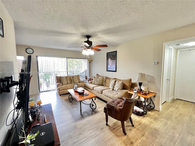 living room with ceiling fan, light hardwood / wood-style flooring, and a textured ceiling