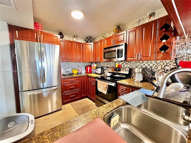 kitchen featuring light stone countertops, appliances with stainless steel finishes, sink, and backsplash