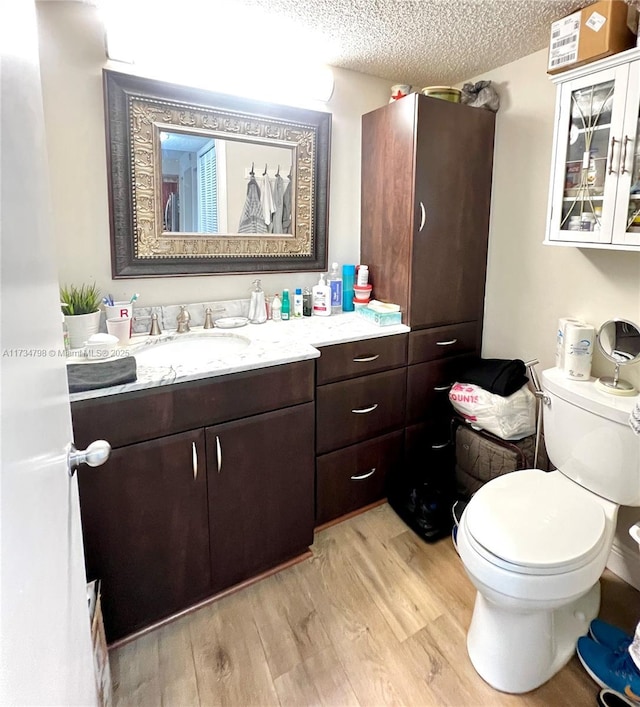 bathroom with hardwood / wood-style flooring, vanity, a textured ceiling, and toilet