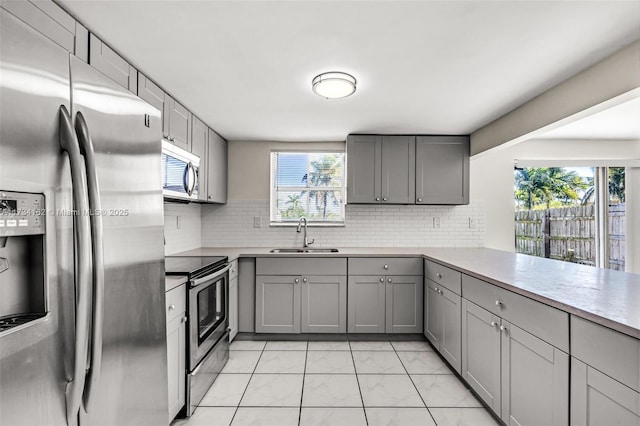 kitchen featuring appliances with stainless steel finishes, sink, decorative backsplash, and gray cabinetry