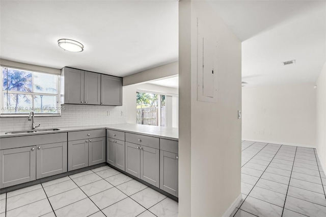 kitchen featuring tasteful backsplash, a healthy amount of sunlight, sink, and gray cabinetry