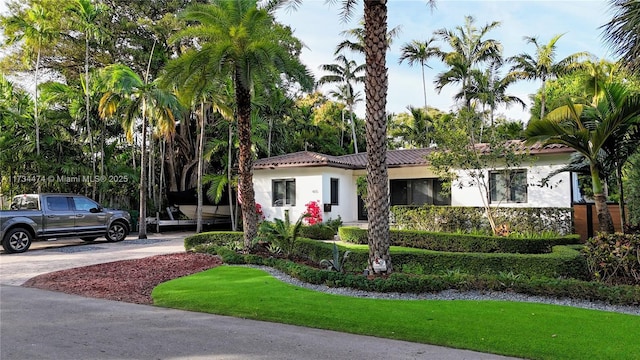 view of front facade featuring driveway, stucco siding, and a tile roof