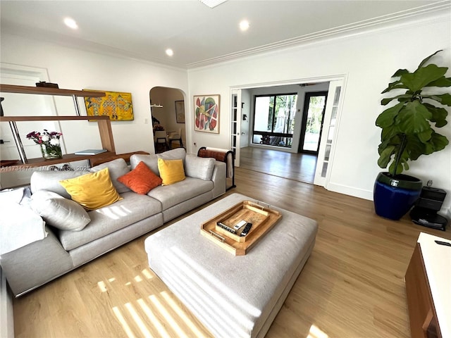 living area with crown molding, baseboards, wood finished floors, recessed lighting, and arched walkways