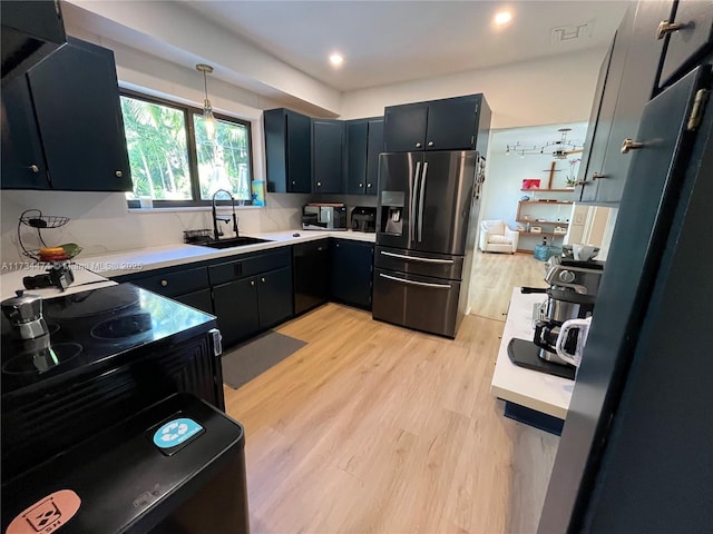 kitchen with pendant lighting, sink, light hardwood / wood-style flooring, and black appliances