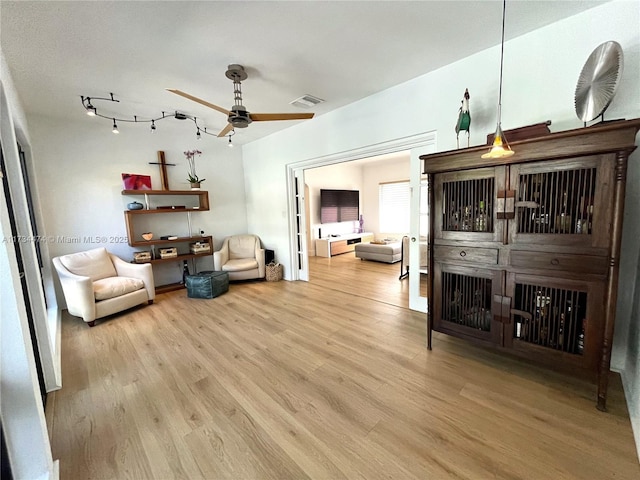 living room with visible vents, wood finished floors, and ceiling fan