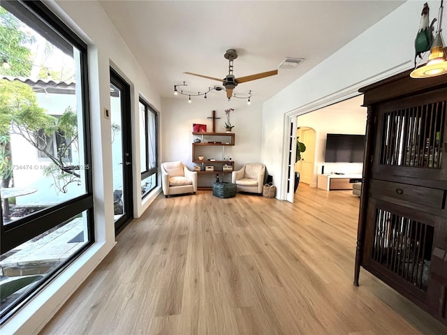 living area with a ceiling fan, visible vents, and light wood-type flooring