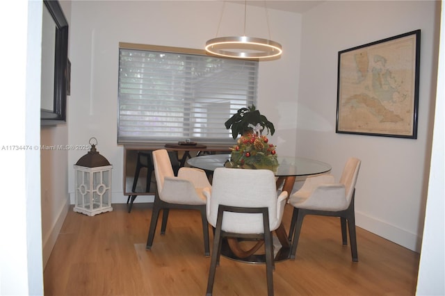 dining space with baseboards, wood finished floors, and a chandelier