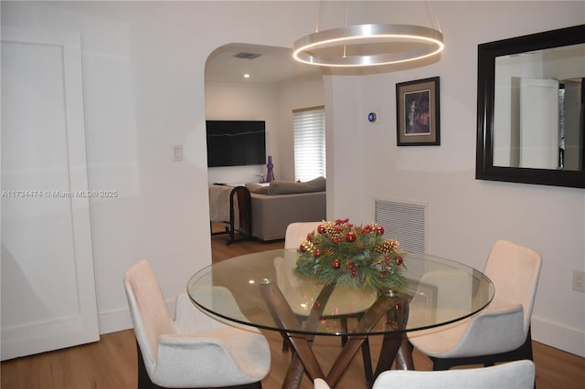 dining area with visible vents, arched walkways, and wood finished floors