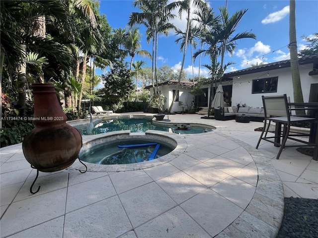 pool with an outdoor hangout area, an in ground hot tub, and a patio
