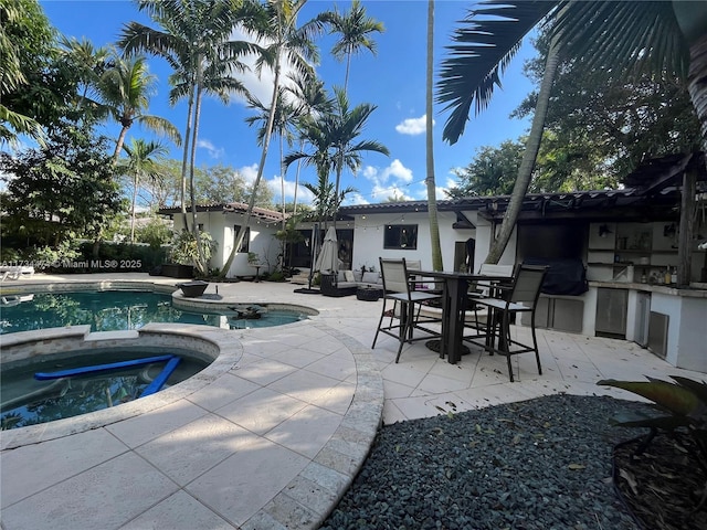 view of swimming pool with an in ground hot tub, area for grilling, and a patio