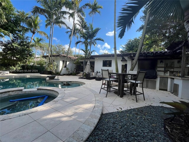 view of swimming pool with a patio, exterior kitchen, outdoor dining space, and a pool with connected hot tub