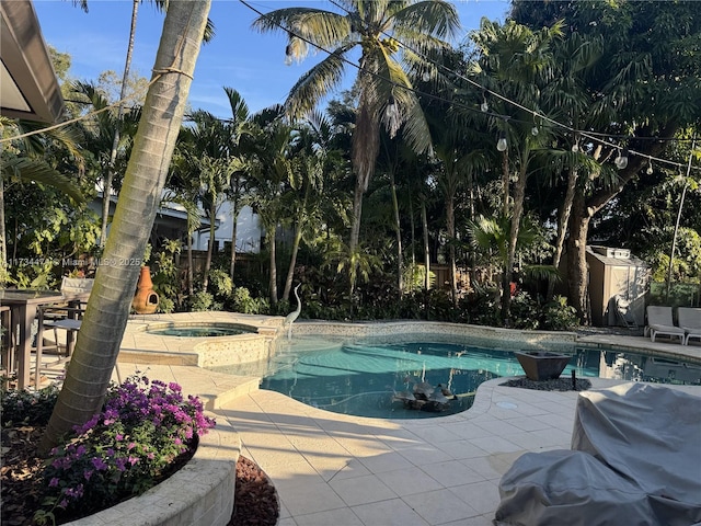 view of pool featuring a pool with connected hot tub, an outbuilding, a storage shed, a fenced backyard, and a patio