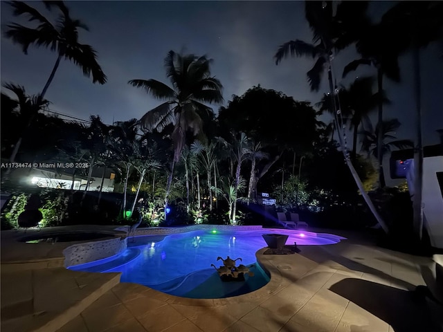 pool at night with a patio area