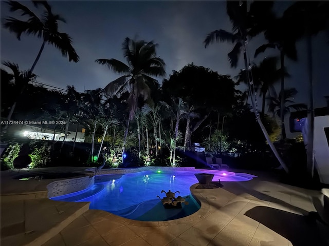 pool at twilight featuring a fenced in pool, an in ground hot tub, and a patio area