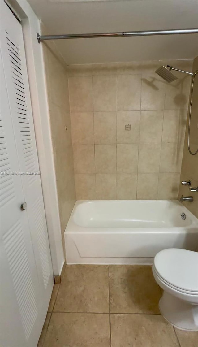 bathroom featuring tile patterned flooring, tiled shower / bath, and toilet