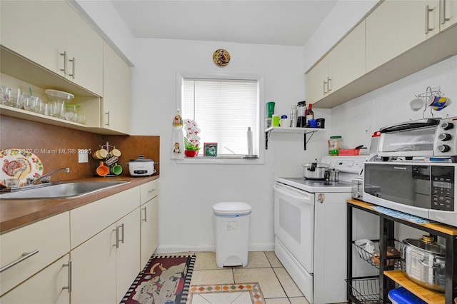 kitchen featuring cream cabinets, sink, light tile patterned floors, and electric stove