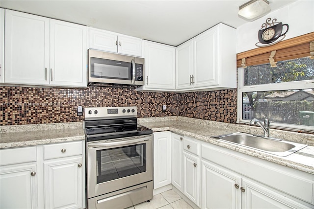 kitchen with sink, light tile patterned floors, appliances with stainless steel finishes, backsplash, and white cabinets