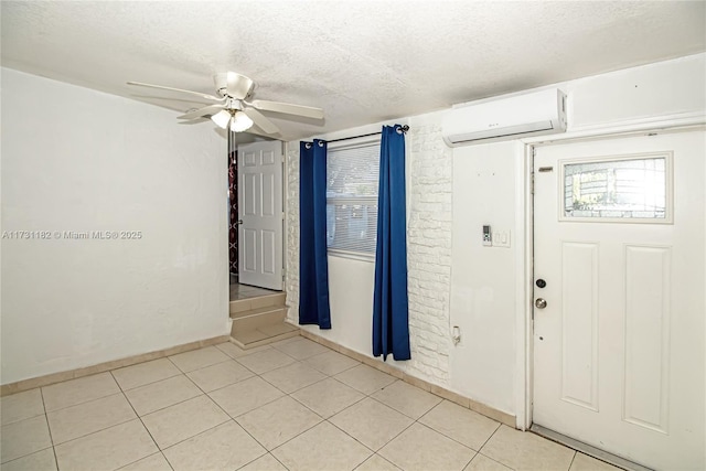 tiled foyer featuring ceiling fan, a wealth of natural light, a wall mounted air conditioner, and a textured ceiling