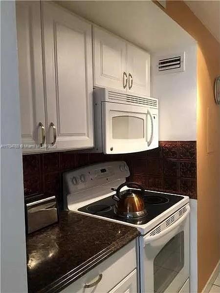 kitchen featuring white cabinetry, white appliances, and tasteful backsplash