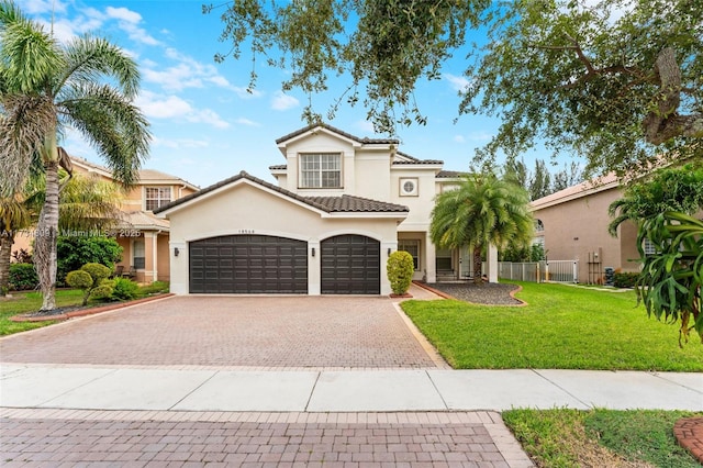 mediterranean / spanish home with a tile roof, a front yard, decorative driveway, and stucco siding