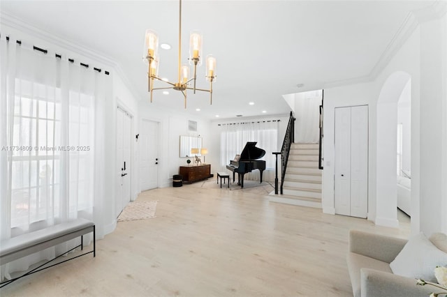 entryway featuring arched walkways, recessed lighting, stairs, light wood-type flooring, and crown molding