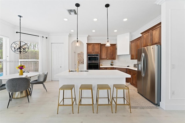 kitchen with visible vents, a kitchen island with sink, stainless steel appliances, premium range hood, and a sink