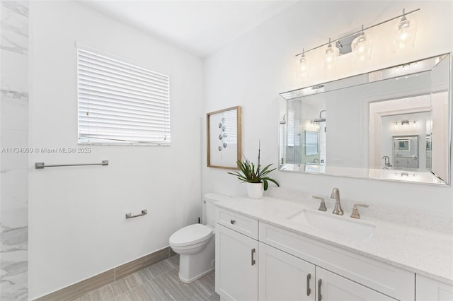 bathroom featuring walk in shower, vanity, toilet, and baseboards