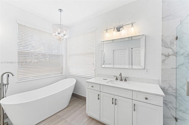 full bath featuring a marble finish shower, baseboards, an inviting chandelier, a freestanding bath, and vanity